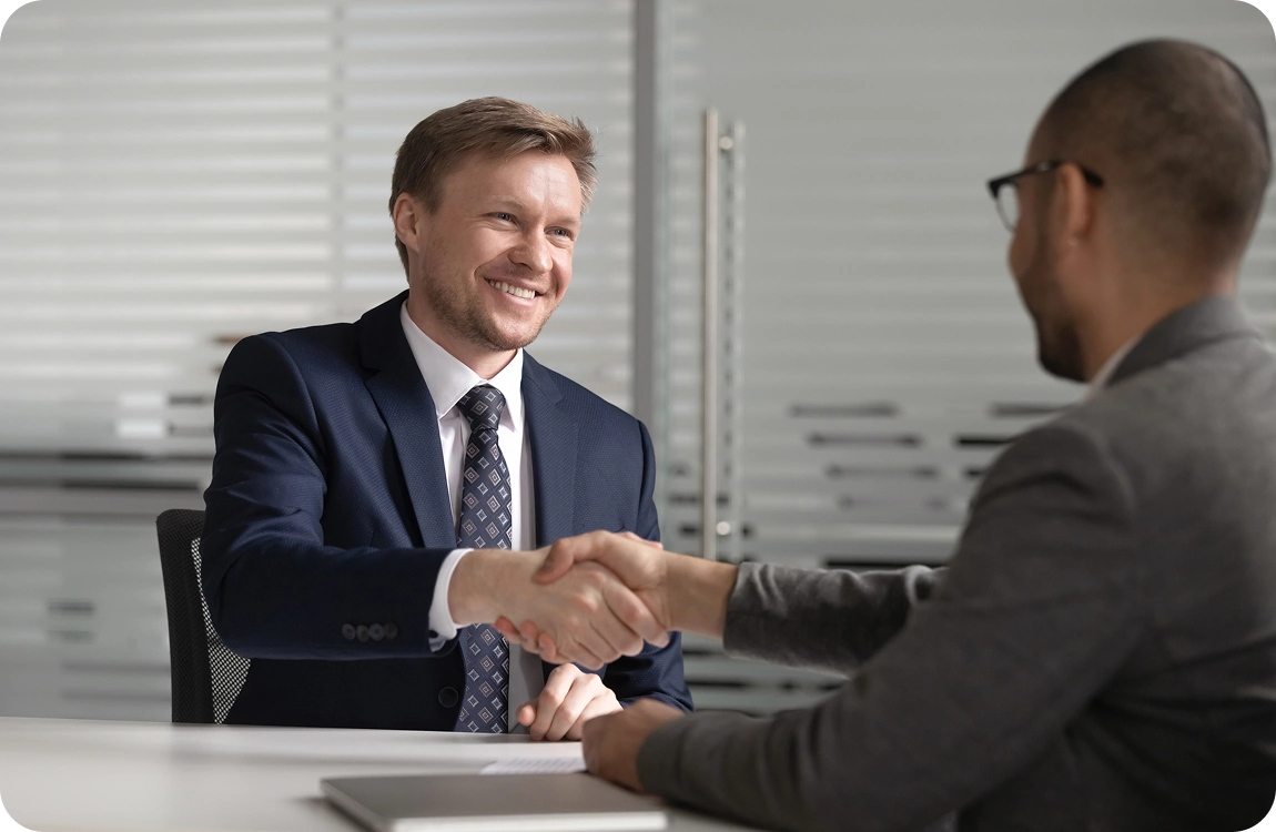 Two men shaking hands in office meeting.