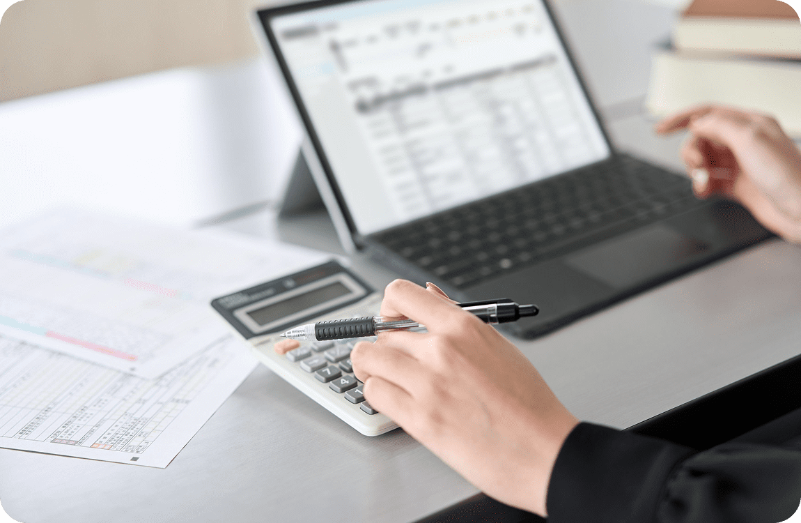 Person using calculator and laptop for calculations.